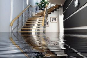 Flooded interior space with standing water, wooden staircase, and modern decor, illustrating significant water damage indicative of a foundation leak.