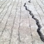 Cracked surface indicating potential slab leak damage in plumbing, featuring visible fractures and textured ground.