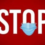 Stop sign with a blue face mask, emphasizing health and safety measures related to water safety and plumbing services.