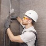 Construction worker using shower installation equipment at a bathroom remodeling site for Marc Francis Plumbing.