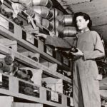 Woman in work attire organizing plumbing supplies on shelves, highlighting women's contributions to the plumbing industry.