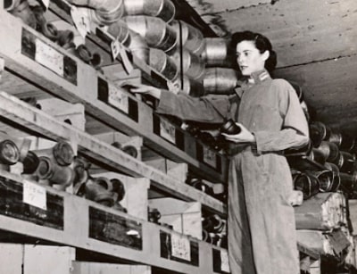 Woman in work attire organizing plumbing supplies on shelves, highlighting contributions of women in plumbing history, related to Lillian Ann Baumbach's legacy.