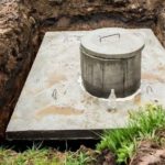 Concrete structure at an excavation site with a circular lid, relevant to Marc Francis Plumbing's septic system maintenance.