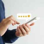 Hand holding a smartphone displaying five-star ratings for Marc Francis Plumbing services in Johnson City, TN.