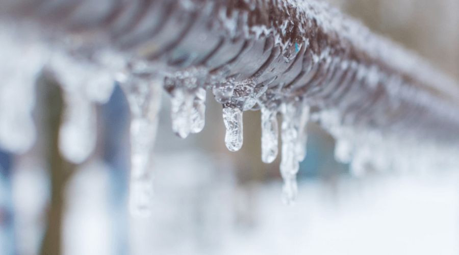 Icicles hanging from a metal pipe, indicating potential frozen pipes, relevant to plumbing issues during winter.