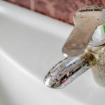 Close-up of a worn faucet showing corrosion, highlighting issues related to hard water in plumbing systems.