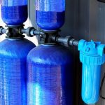Bright blue water filtration tanks with plumbing connections from Marc Francis Plumbing's efficient installation services.
