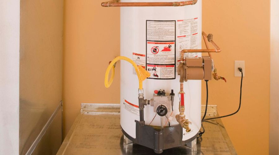 White water heater with copper pipes and safety warnings for plumbing maintenance by Marc Francis Plumbing.