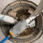 Sump pump installation in a sump pit, showcasing water-powered backup system and plumbing connections for flood prevention in homes.