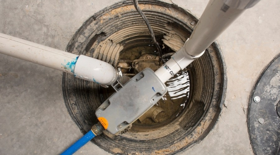 Sump pump installation with pipes and electrical components in a sump pit, illustrating flood protection solutions.